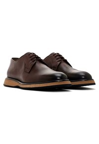 Scarpe in pelle marrone con punta rotonda, design allacciato e suola in gomma stratificata. Texture liscia, cuciture minime e finitura elegante.