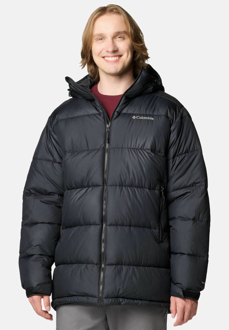 Giubbotto nero in piuma con zip frontale, cappuccio e polsini elasticizzati. Presenta un design trapuntato e il logo Columbia sul lato sinistro del petto.