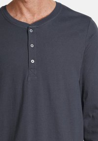 Chemise henley à manches longues gris foncé avec col arrondi, patte de boutonnage à cinq boutons et tissu en coton lisse avec un léger stretch.