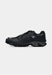 Black and gray trail running shoe with textured sole, quick-lace system, and mesh upper for breathability and support.