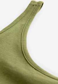 Oliwkowy top na ramiączkach z okrągłym dekoltem i wąskimi ramiączkami. Miękka, gładka tekstura z delikatnym detalem przeszycia wzdłuż krawędzi.