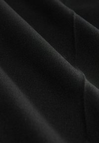 Sort stof med en glat tekstur, foldet i bløde draperinger, der viser et ensartet udseende uden mønstre eller accenter.