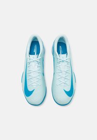 Des crampons de football Nike Mercurial bleu clair avec des lacets blancs et des logos swoosh bleus bien visibles, vus du dessus sur un fond blanc.