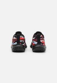 Baskets à motif camouflage noir et rouge avec une semelle noire texturée et une languette au talon. Caractéristiques d'un design élégant et léger.