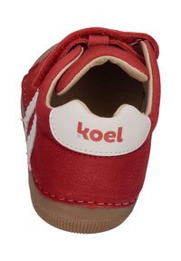 Red leather shoe with white accents and a textured finish. Features a round toe and a bow detail on the front, labeled with "koel."