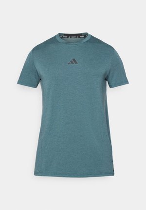 Türkise lühikeste varrukatega sportlik särk, mis on valmistatud siledast kangast. Ees on must Adidas'i logo ja särk on varustatud ümberkaela disainiga.