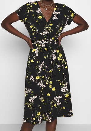 Robe portefeuille florale noire avec des fleurs jaunes et roses, manches courtes, décolleté en V, ceinture nouée à la taille, longueur genoux, tissu léger.