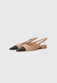 Ballerines à talon escarpin avec un corps en cuir nude et un capuchon pointu noir. Présentent un petit talon carré et une bride ajustable à la cheville.