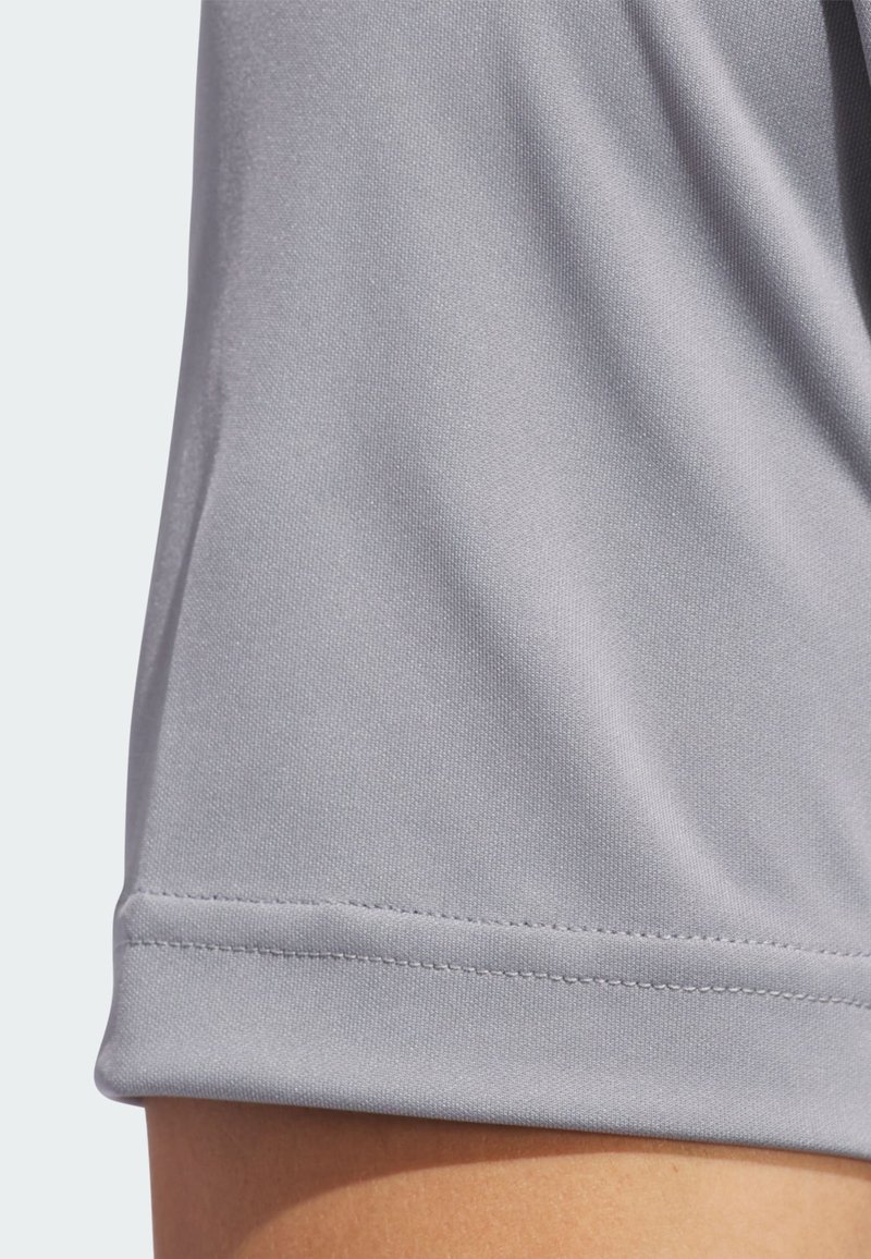 Tissu de sport gris présentant une texture lisse, une finition légèrement brillante et un ourlet avec un détail de couture visible.