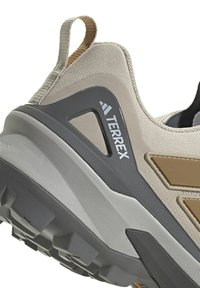 Primo piano di un tallone di scarpa da escursionismo Adidas Terrex beige e grigio, con suola robusta e linguetta di estrazione.