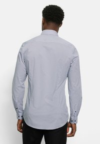 Langarmhemd in Hellblau mit geometrischem Muster. Verfügt über einen Kentkragen, Knopfmanschetten und einen geraden Saum mit einer leicht taillierten Passform.