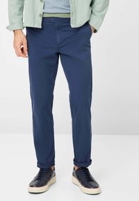 Navyblauwe katoenen broeken met een slim fit, met een platte voorkant, zijzakken en opgerolde boorden, gecombineerd met zwarte sneakers.