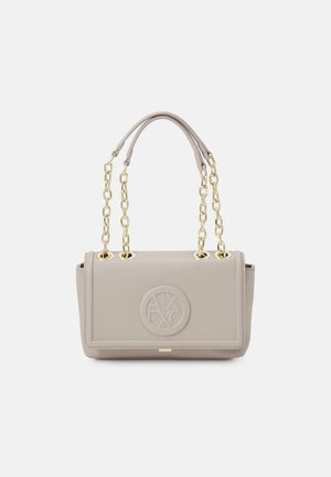 Sac à main rectangulaire beige clair avec double chaîne dorée et poignées en cuir, logo circulaire embossé sur le rabat avant.