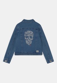 Chaqueta de denim en azul oscuro con un diseño recortado. Presenta un gráfico de calavera floral blanca en la parte posterior, dobladillo trenzado y herrajes plateados.