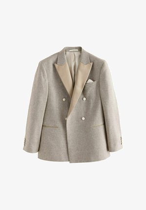 Világos bézs színű, dupla gombos blézer széles szatén hajtókákkal, négy gombbal, két zsebbel és egy zsebkendővel, fehér háttéren bemutatva.