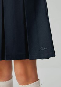 Fustă plisată bleumarin dintr-un material texturat, cu un model de cusătură vizibil. Dispune de un mic logo brodat "Clarks" la tiv.