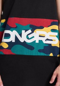 Svart oversized skjorte med et fargerikt kamuflasjemønster i rødt, grønt, gult og blått, samt en fremtredende hvit "DNGRS" logo.
