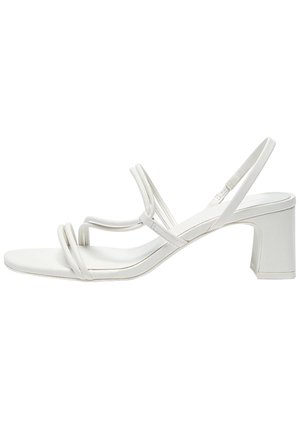 White heeled sandal with thin double front straps, a slingback strap, and a block heel on a white background.