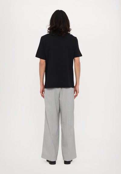 Black cotton crew neck t-shirt paired with light gray wide-leg trousers. Both garments have a relaxed fit and minimal design, no visible patterns.