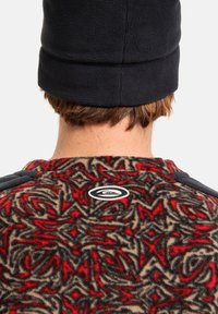 Pullover in fleece marrone con motivo floreale in rosso e nero. Presenta un berretto nero, colletto rotondo e un logo sulla schiena.