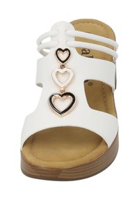 Sandale blanche à bout ouvert avec trois accents en forme de cœur, dotée d'une semelle intérieure douce couleur tan et d'une semelle externe texturée marron. Design à bride ajustable.