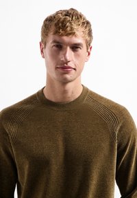 Olijfgroen gebreid sweater met geribbelde accenten op de schouders, ronde halslijn en zachte textuur. Eenvoudig, aansluitend ontwerp met minimale naden.