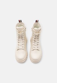 Beige hoge laarzen van soepel leer, met voorveters, een zijrits en een gestructureerde zool met een contrasterende trekband.