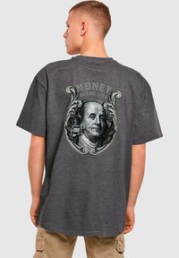 Sivina majica s kratkimi rokavi v sivi barvi, ki prikazuje velik grafični motiv Benjamina Franklina z besedilom "DENAR NIKOLI NE LAŽE" v okrasnem okvirju.