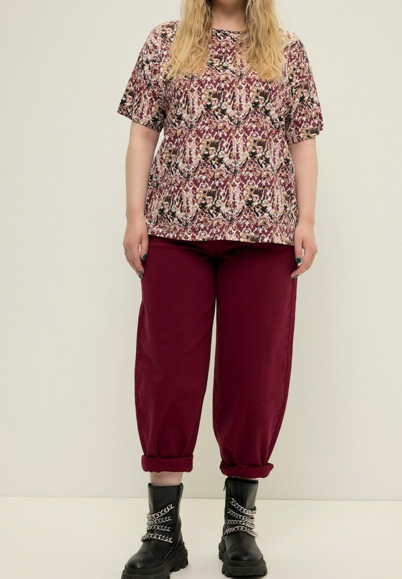 Lyhyet hiharat kukkakuosisessa paidassa burgundin sävyissä, yhdistettyinä löysiin burgundinvärisiin housuihin ja mustiin sotakengissä, joissa on ketjusomisteita.