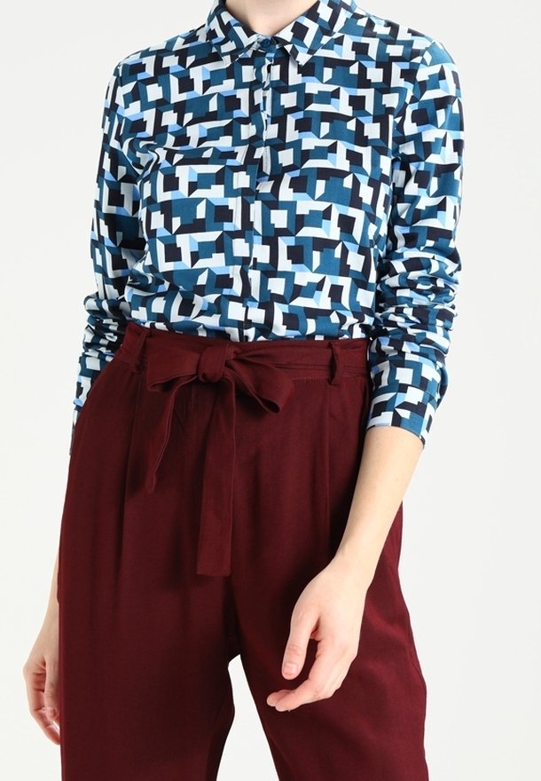 Long-sleeve button-up shirt in blue tones with a geometric pattern; paired with high-waisted burgundy pants featuring a tied belt.