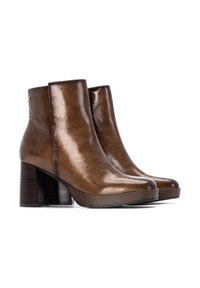 Botas de tobillo de cuero marrón con un acabado brillante, tacón cuadrado, punta redonda y suela de plataforma. Presentan un logotipo de acento lateral cerca del tacón.