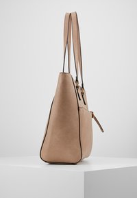 Borsa tote in pelle marrone con doppie tracolle, forma strutturata, dettagli neri e chiusura laterale con zip. Texture liscia, design minimalista.