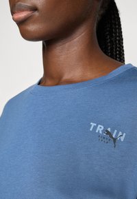 Blauwe katoenen t-shirt met ronde hals, voorzien van het woord "TRAIN" en een zwart logo op de voorkant. Gladde textuur, casual stijl.