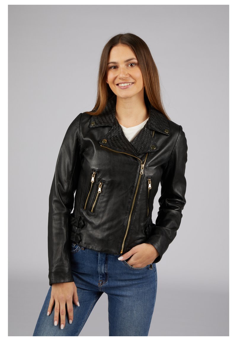 Schwarze Leder-Motorradjacke mit geflochtenem Kragen, zwei vorderen Reißverschlusstaschen und goldenen Hardware-Details. Trägt man über einem weißen Oberteil und blauen Jeans.