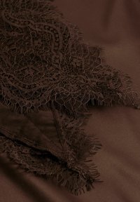 Pruun satiinriie musta pitsi äärise ja keerukate lillemustrite ning lõdva servaga. Sile tekstuur on vastand peenikese pitsiga.