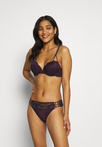 Bordeaux kant bh met gevoerde cups, verstelbare bandjes en decoratieve kantaccenten; bijpassende bikini met kantafwerking en ingewikkelde uitsparingen.