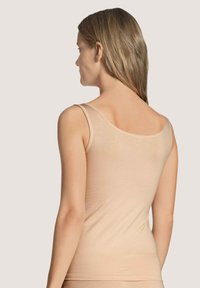 Top a canotta beige chiaro realizzato in materiale morbido ed elasticizzato. Presenta spalline sottili e un design semplice con una silhouette aderente.