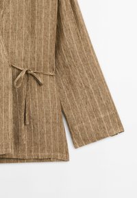 Veste enroulée rayée marron en tissu texturé, avec une taille nouée et des manches larges et ouvertes. Bords propres et design décontracté.