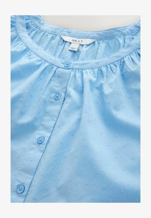 Hellbluse mit rundem Ausschnitt, vorderer Knopfleiste und strukturiertem Stoff mit kleinen Rautenmusterungen. Weiches Baumwollmaterial.