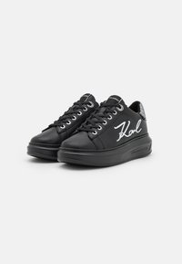 Baskets en cuir noir avec une finition lisse, bout arrondi, semelle noire épaisse et inscription blanche "Karl" sur le côté ; panneau arrière texturé.