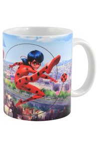 Tazza in ceramica con un design vivace di un personaggio in un vestito rosso con macchie nere, ambientato su uno sfondo di cielo blu e skyline di una città.
