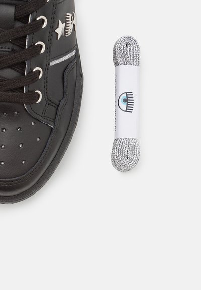 Sneaker in pelle nera con accenti di stelle argentate, perforazioni e suole testurizzate. Include un laccio riflettente argentato arrotolato.
