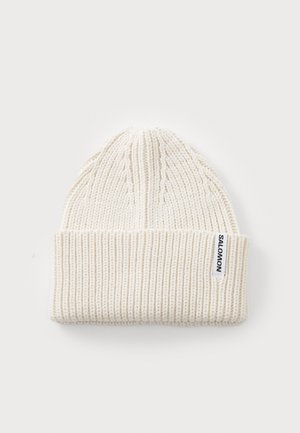 White knit beanie with a ribbed texture, featuring a folded cuff and a small woven label on the side that reads "SALOMON."