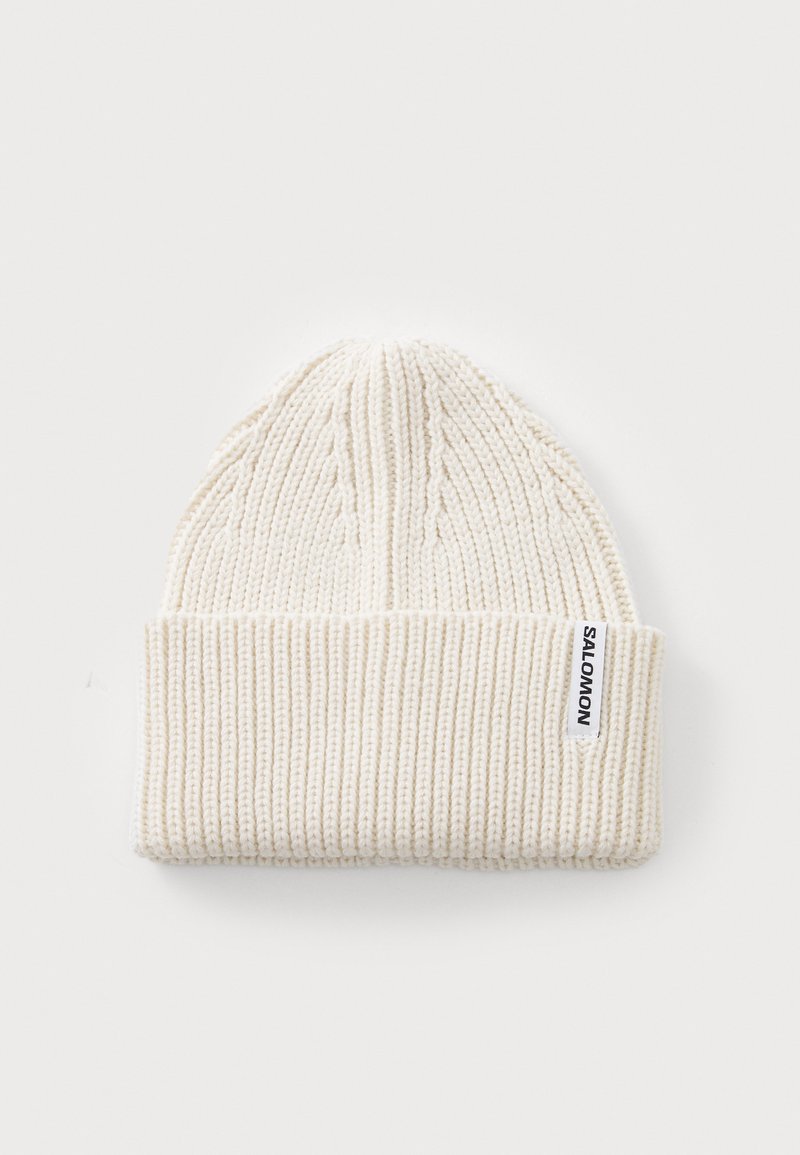 Gorro de malha branco com textura canelada, apresentando uma aba dobrada e uma pequena etiqueta tecida na lateral que diz "SALOMON."