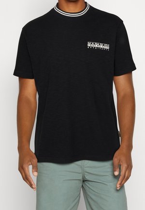 Camiseta de algodón negra con mangas cortas, presenta un cuello a rayas y un logo en texto blanco en la parte del bolsillo del pecho izquierdo.