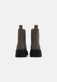 Botas Chelsea de cuero marrón con paneles elásticos laterales y tiradores. Suela gruesa de goma negra con un pequeño tacón para mayor soporte elevado.