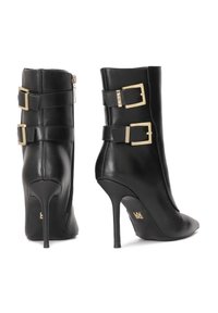 Botine negre din piele, cu vârf ascuțit, toc înalt stiletto și două accesorii cu cataramă aurie la glezne, având un fermoar pe lateral.