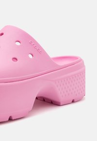 Sabot rose épais à enfiler avec des trous de ventilation, une semelle plateforme texturée et le nom de la marque embossé sur la tige.