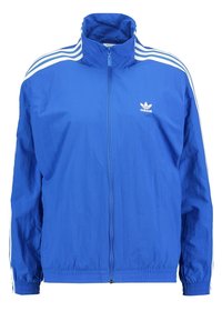 Blå lättviktsjacka med hög krage, hel dragkedja fram, elastiska ärmslut och vita tre-strips detaljer på ärmarna. Adidas-logotyp på bröstet.