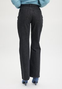 Vysoké čierne džíny z denimu so strihom rovného nohu, obsahujúce dve zadné vrecká a klasický päťvreckový dizajn.